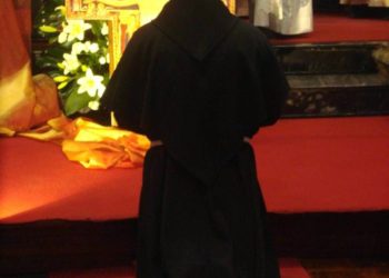 frate francescano in ginocchio davanti al crocifisso